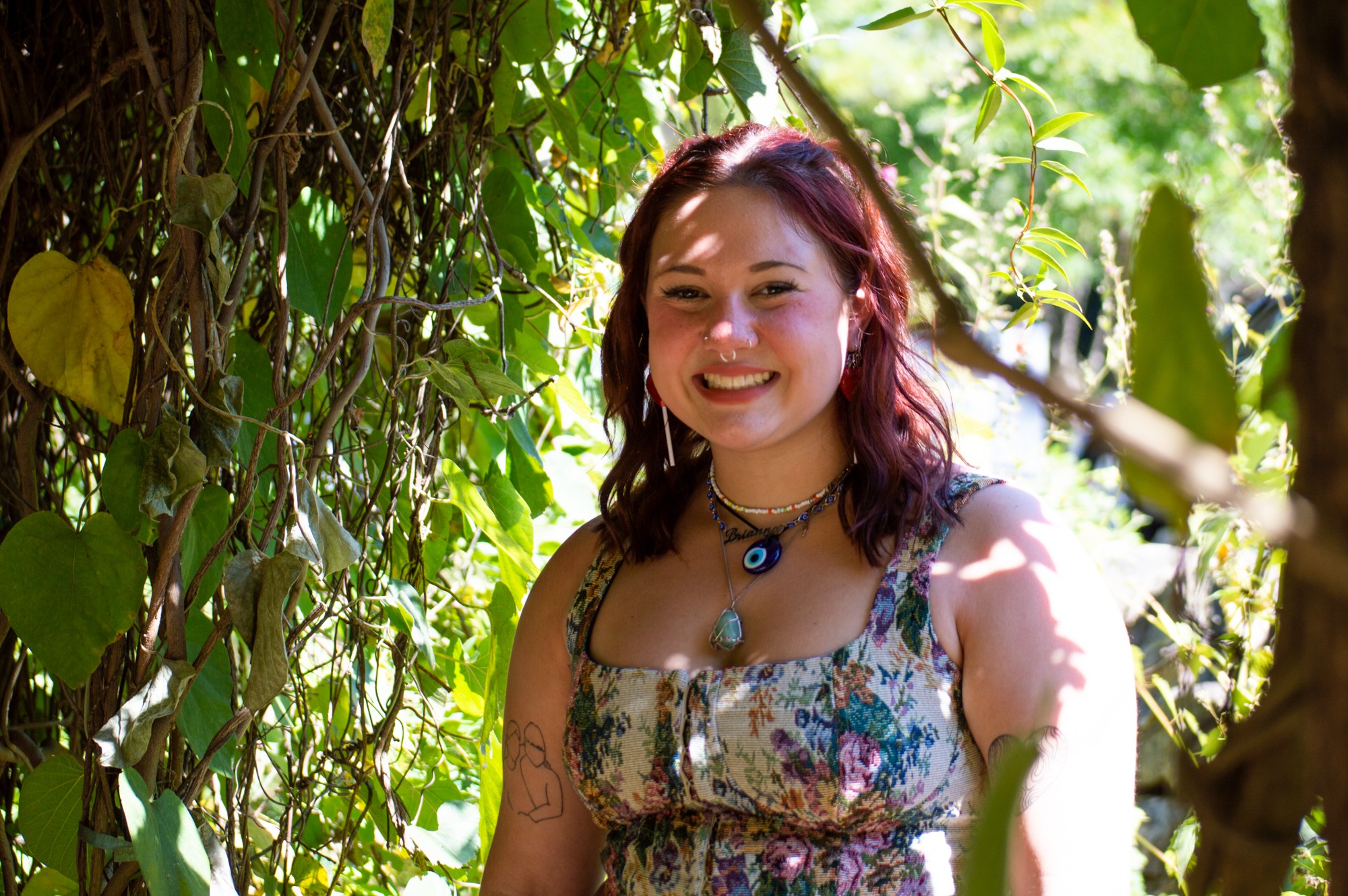 Portrait of Brianna Brigman, a sophomore at UNC, in nature. She has red hair and a floral dress.