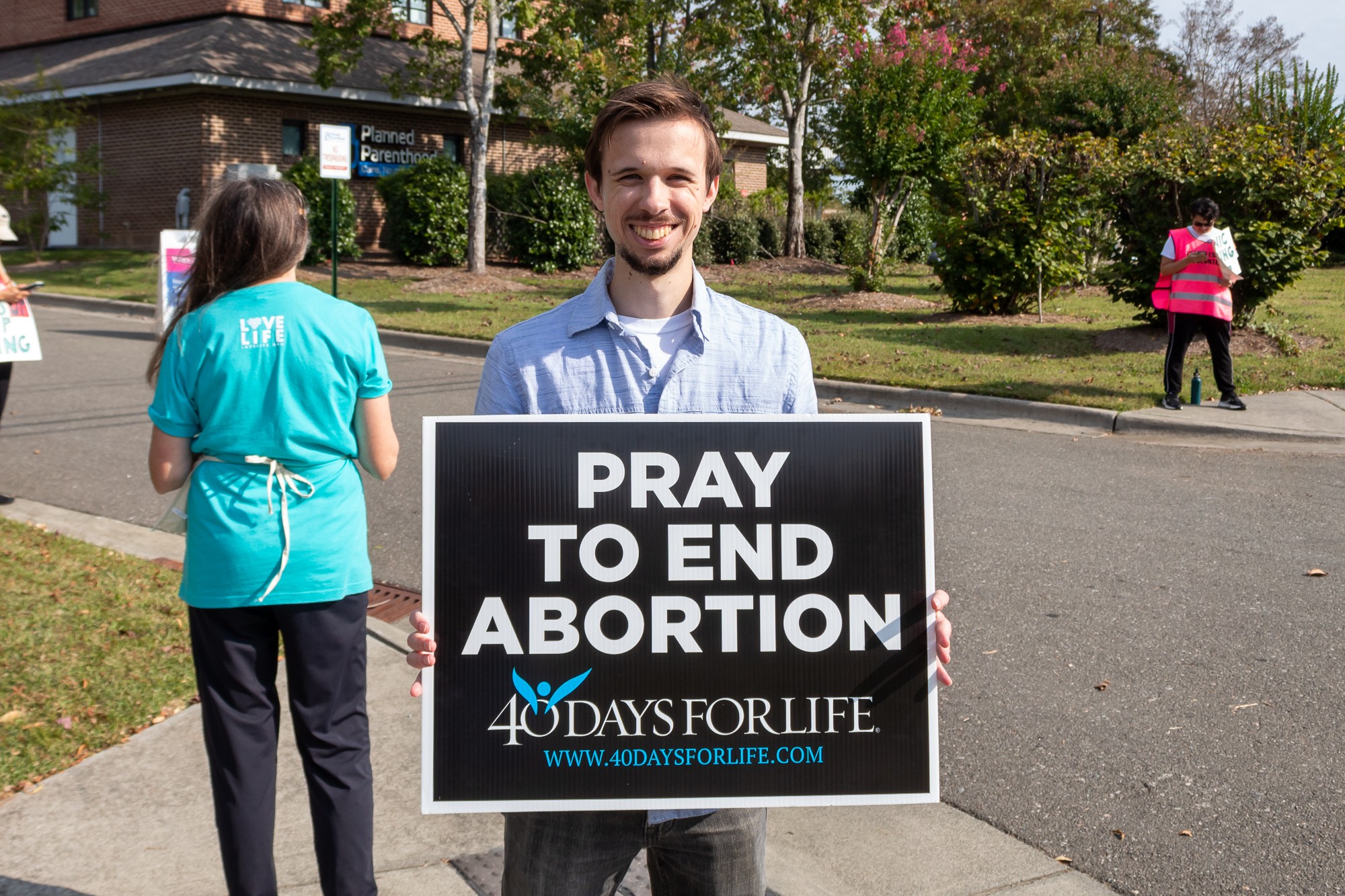 A protester stands outside Planned Parenthood in Chapel Hill. He is poses with his sign that reads “Pray to End Abortion. 40 Days for Life.” Other protestors are in the background.